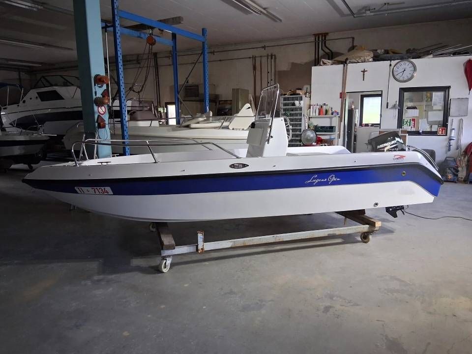 Barca a vela bianca e blu su un rimorchio all'interno di un'officina nautica.