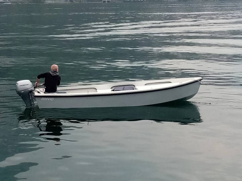 Persona su una piccola barca bianca in acque calme, vista di lato