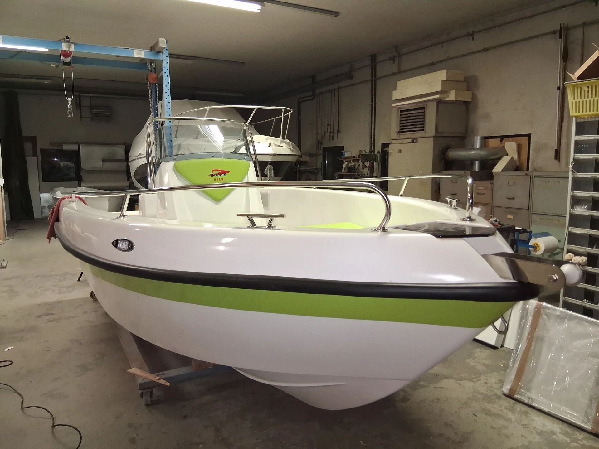 Barca bianca e verde lime su un rimorchio all'interno di un'officina.