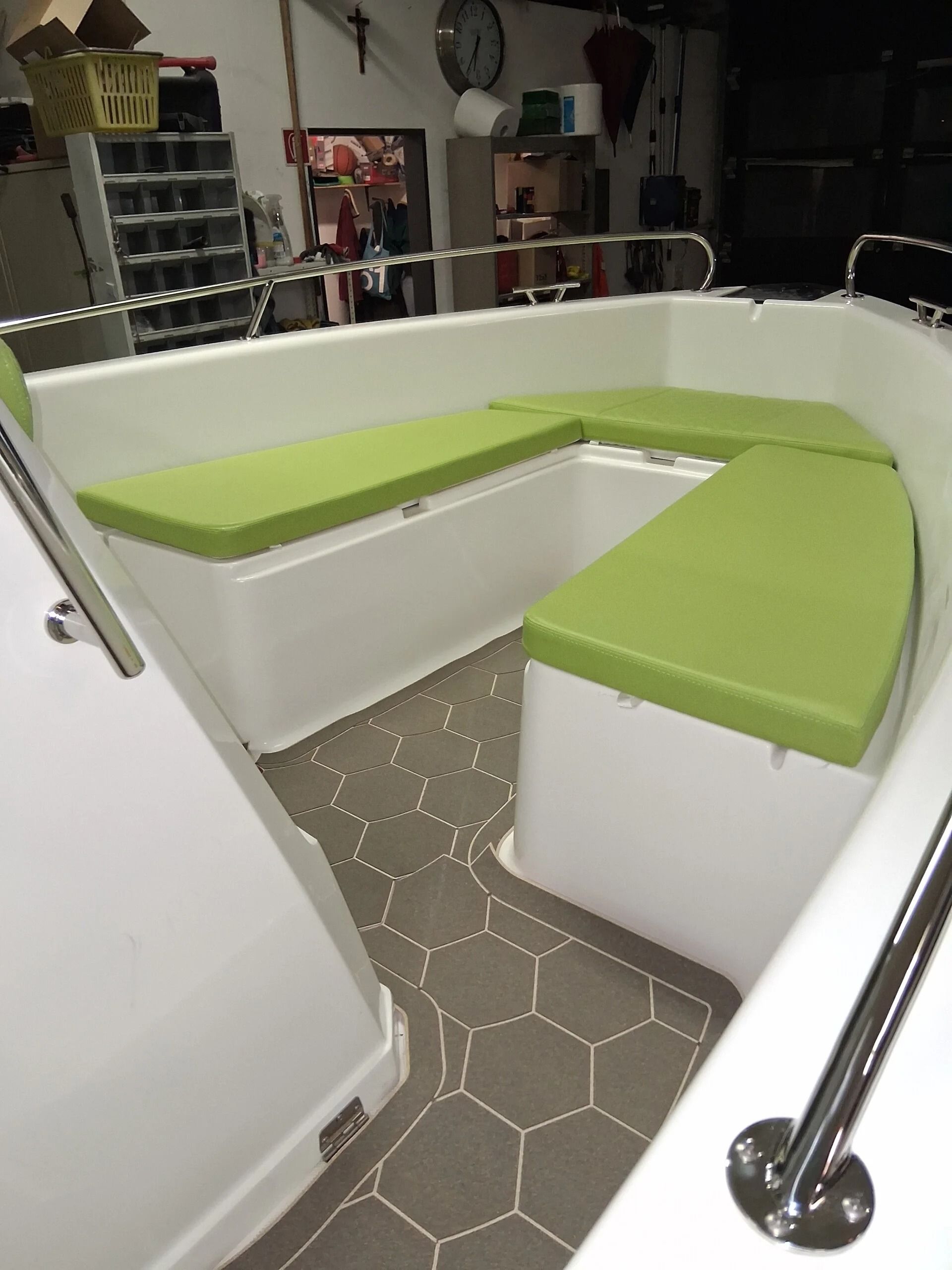 Angolo cucina moderno con panche bianche, cuscini verde lime e pavimento in piastrelle esagonali.