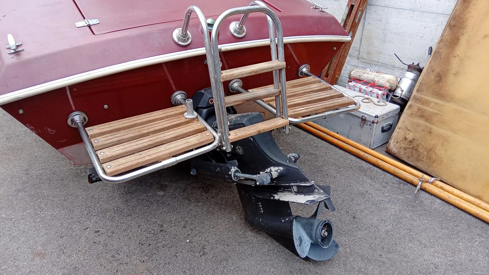 Ti Yachts Sagl
Piccola barca rossa su un rimorchio con una scaletta di metallo e gradini di legno, parcheggiata sul marciapiede vicino a un muro.