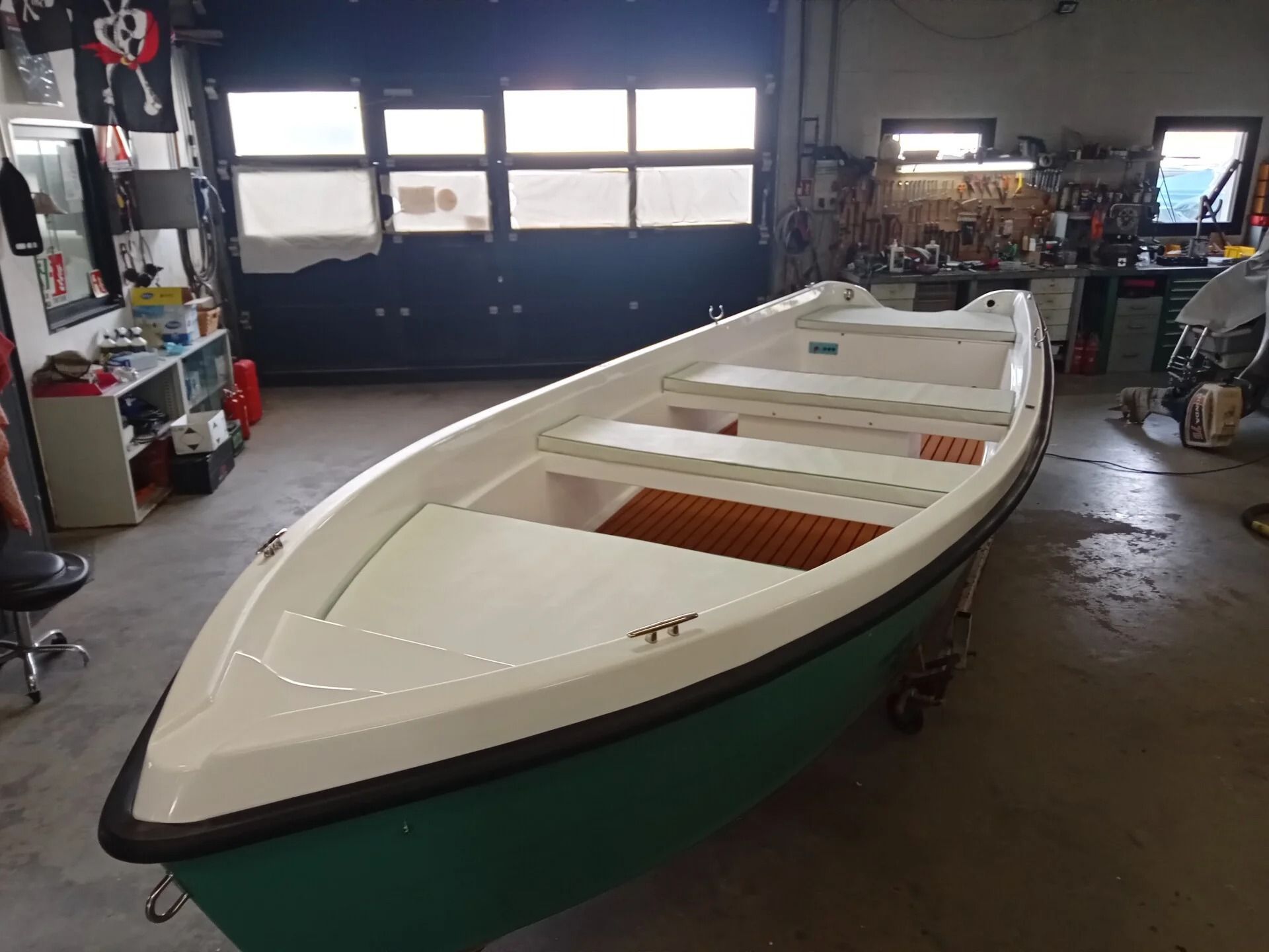 Ti Yachts Sagl 
Barca a remi bianca e verde in un garage, vista dalla prua.
