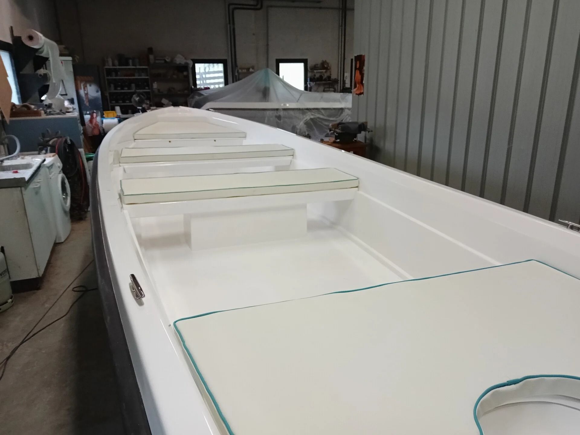 Ti Yachts Sagl 
Scafo di barca bianco in costruzione in un'officina, con supporti per le costole e un'ampia apertura del portello.