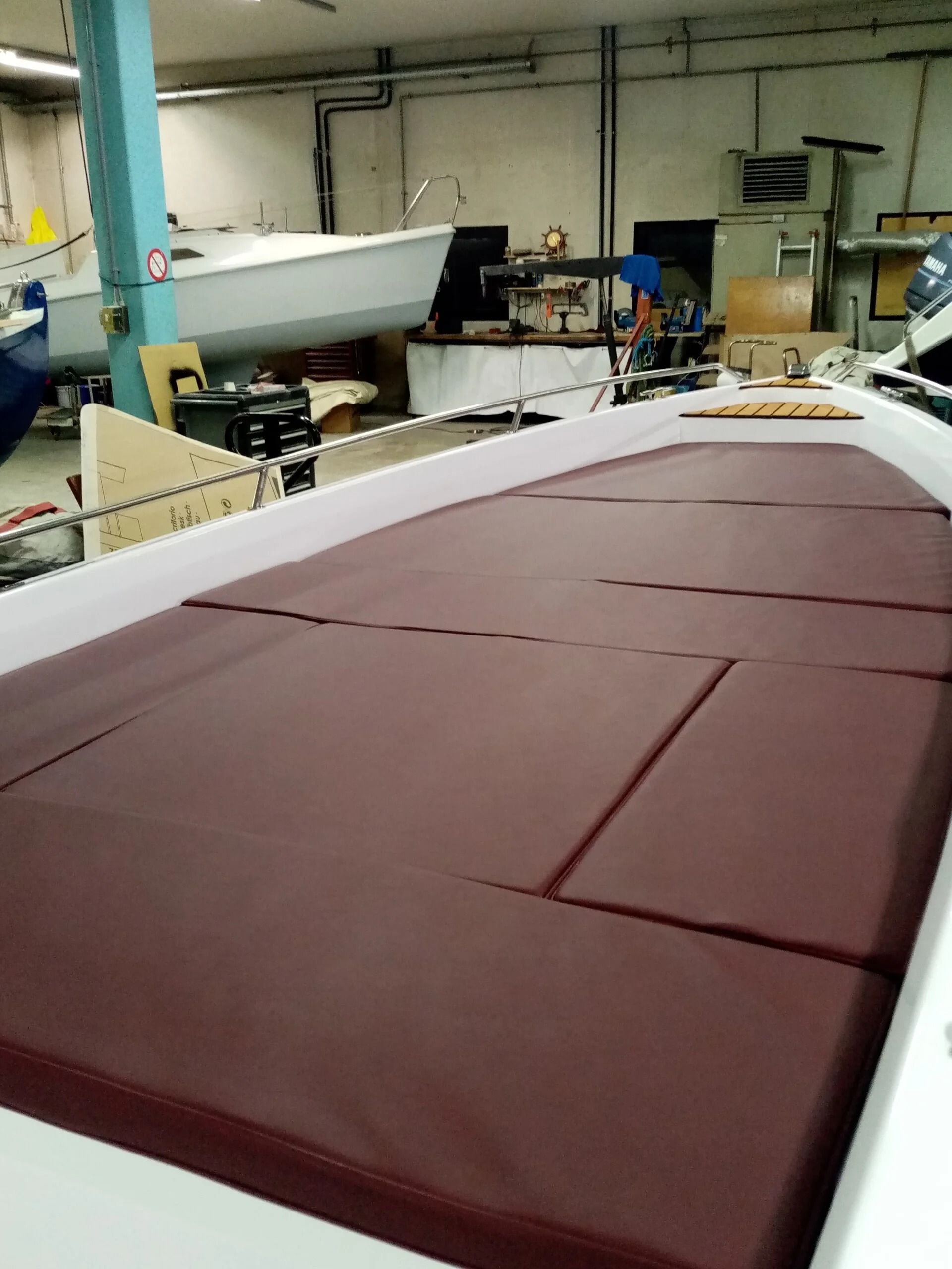 Ti Yachts Sagl 
Tessuto color bordeaux steso in un'officina, disteso su un lungo tavolo vicino a uno stampo per barche.