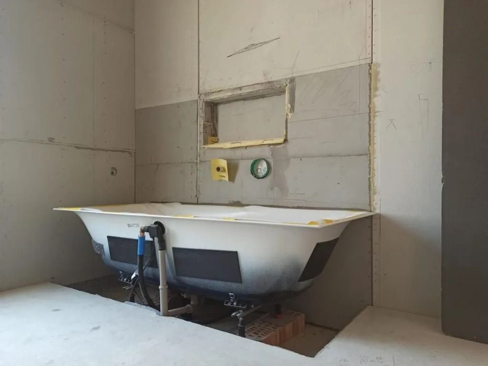 Une baignoire se trouve dans une salle de bain en construction.