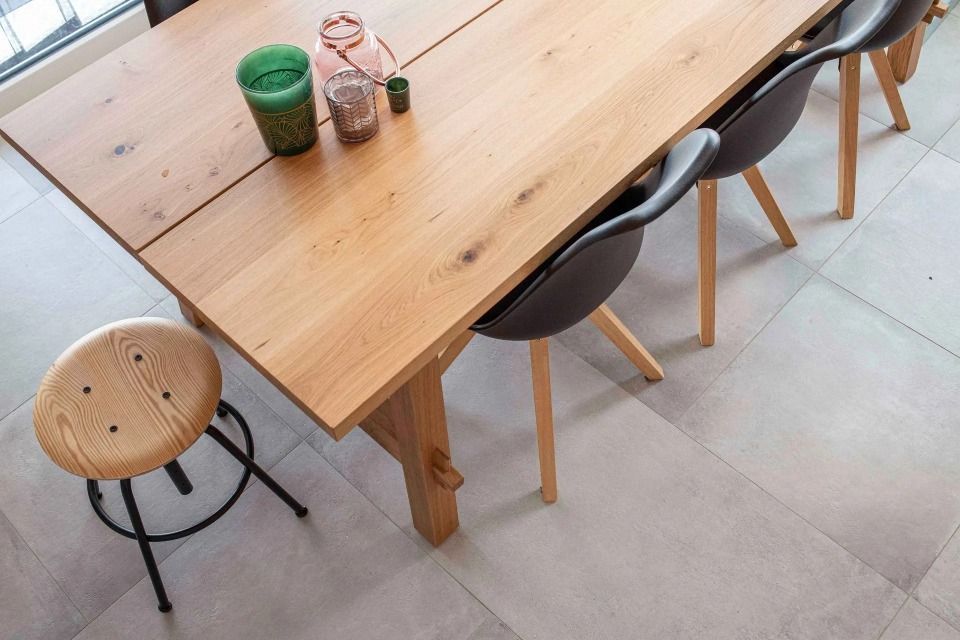 Une table en bois avec des chaises et un tabouret au sol.