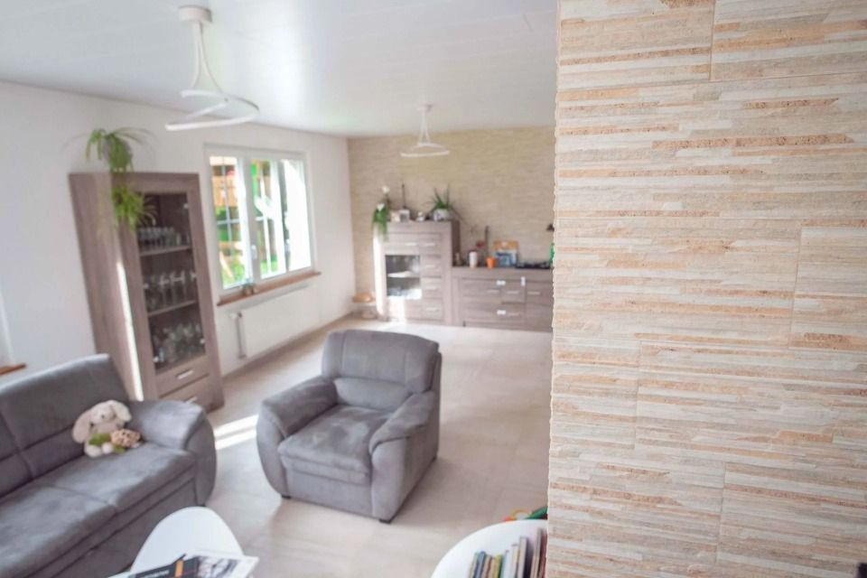 Un salon avec un canapé, une chaise, une table et un mur de briques.