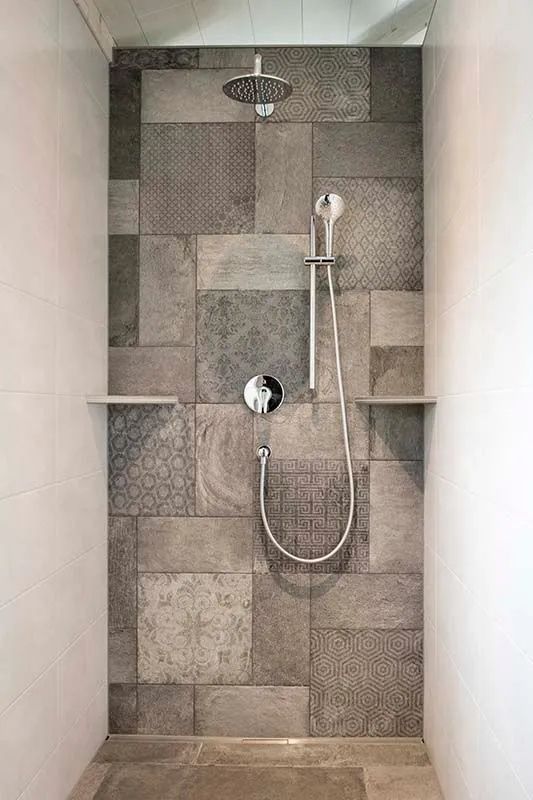 Une douche avec un mur carrelé et un pommeau de douche.