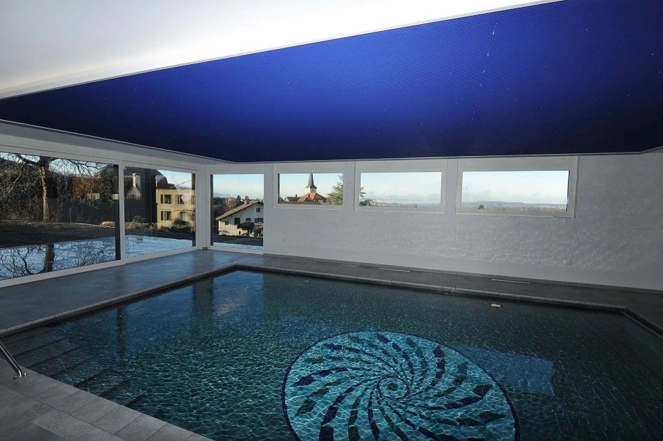 Une grande piscine intérieure avec un plafond bleu