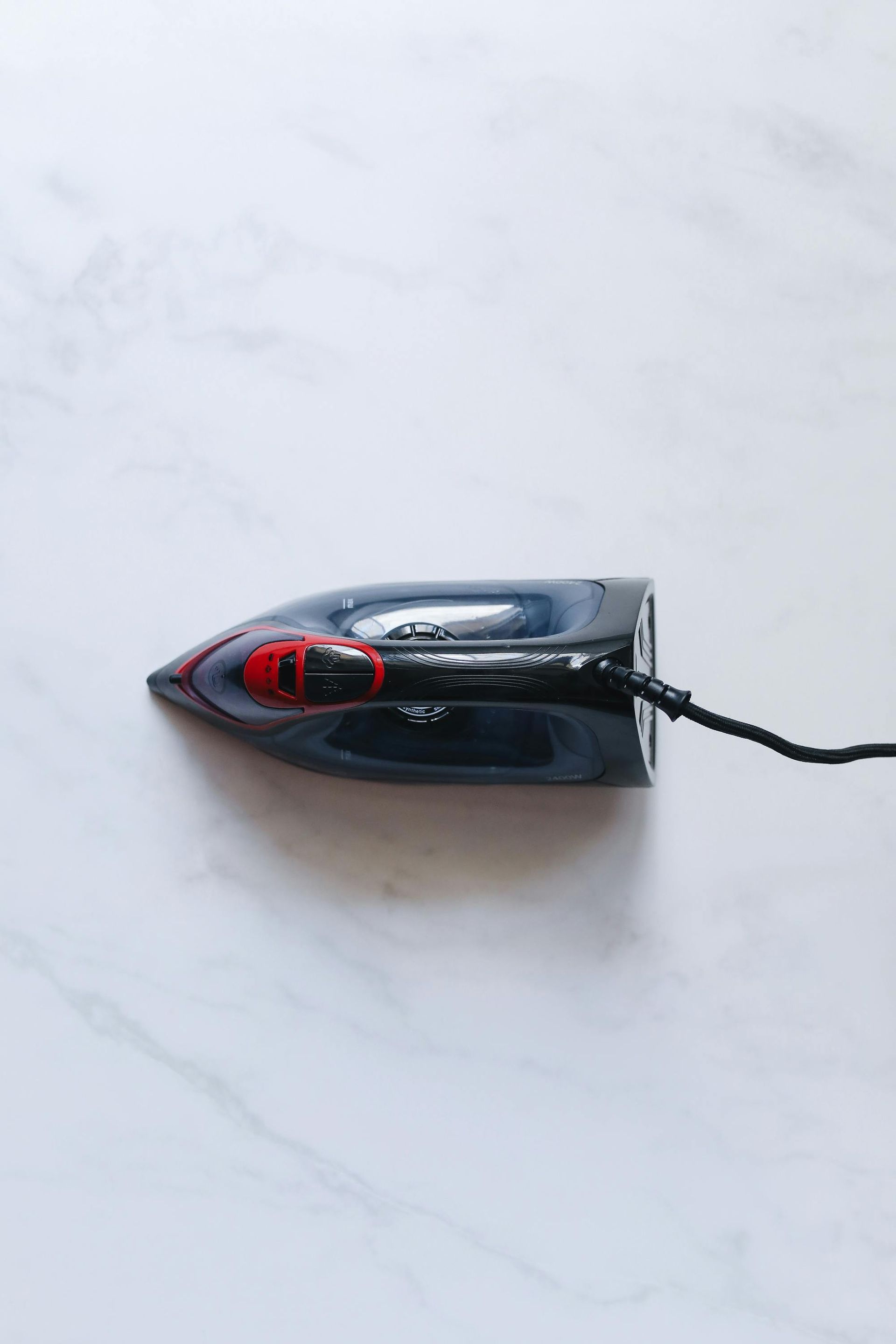 Ein Wäschekorb mit hellblauer Kleidung, einem lila Bügeleisen und blauen Hemden zum Aufhängen.