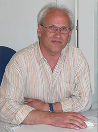 Ein Mann mit Brille und gestreiftem Hemd sitzt an einem Schreibtisch