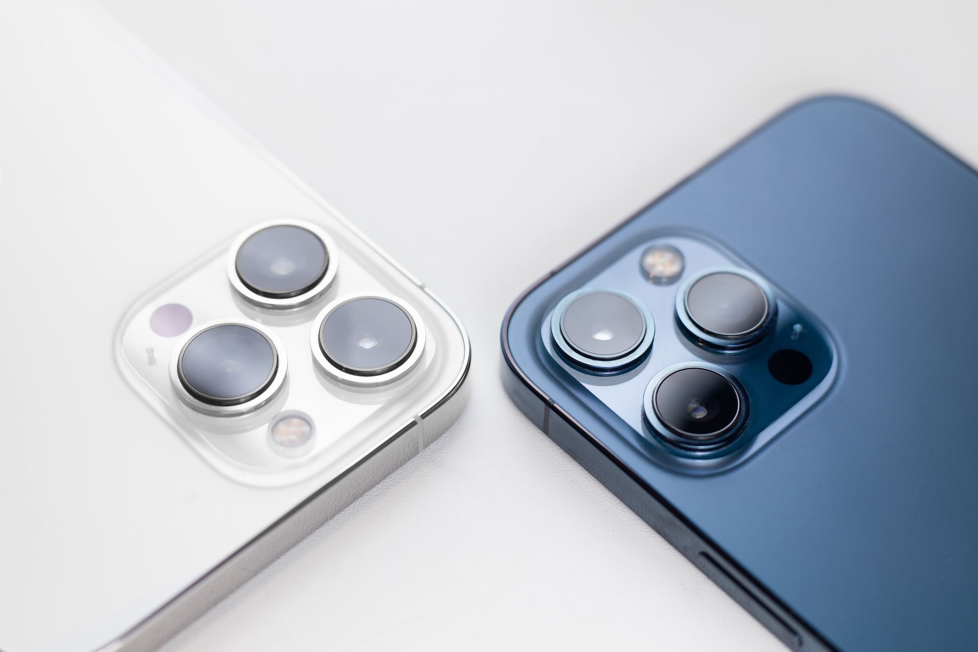 Deux smartphones, l'un argenté et l'autre bleu, positionnés côte à côte, montrant leurs systèmes de triple caméra.