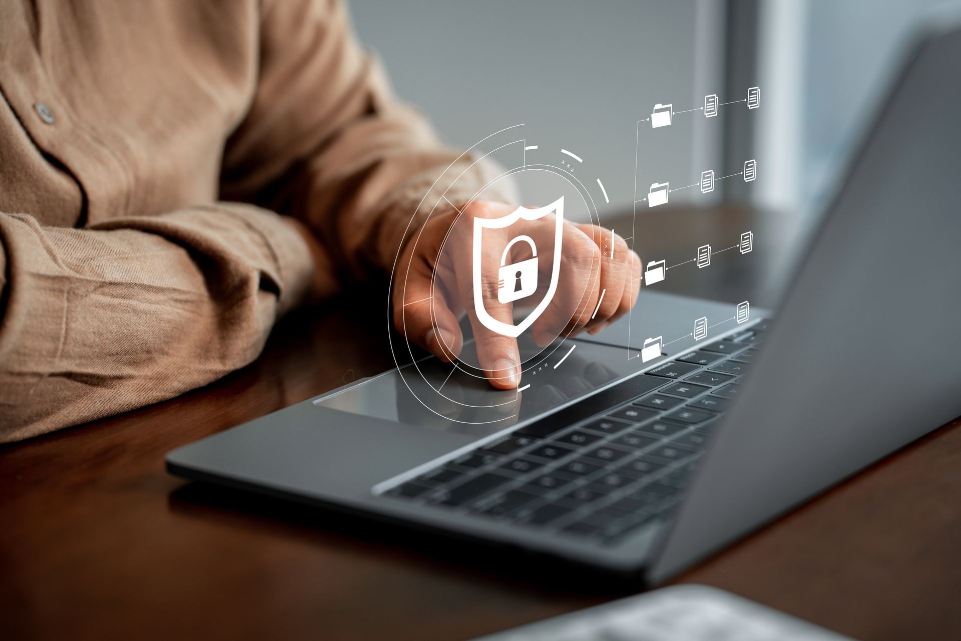 Le doigt d'une personne effleure le pavé tactile d'un ordinateur portable, sur lequel se superposent un bouclier numérique et une icône de cadenas représentant la cybersécurité.