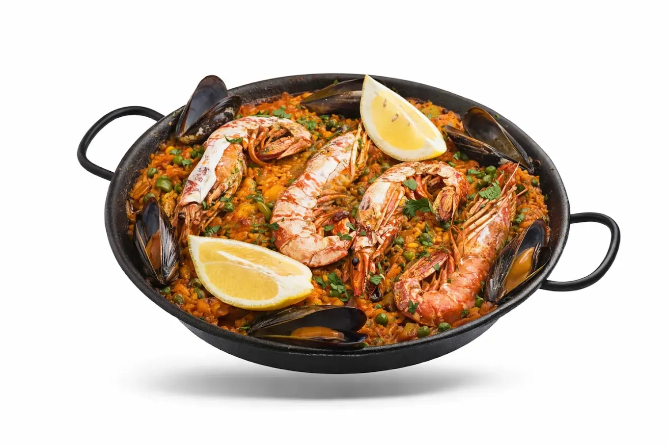 Paella en una sartén negra con gambas, mejillones y rodajas de limón.