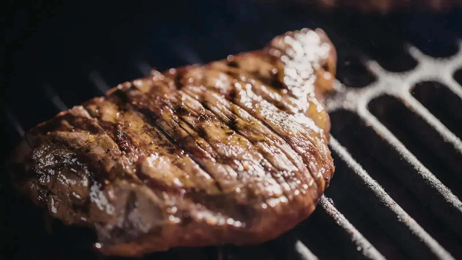 Filete asándose a la parrilla, con marcas de la barbacoa y jugos chisporroteantes.