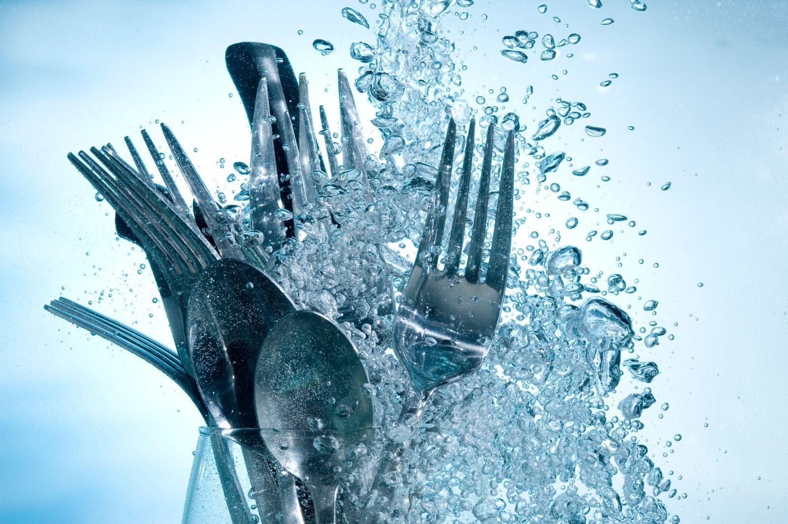Los cubiertos están salpicando en un vaso de agua.
