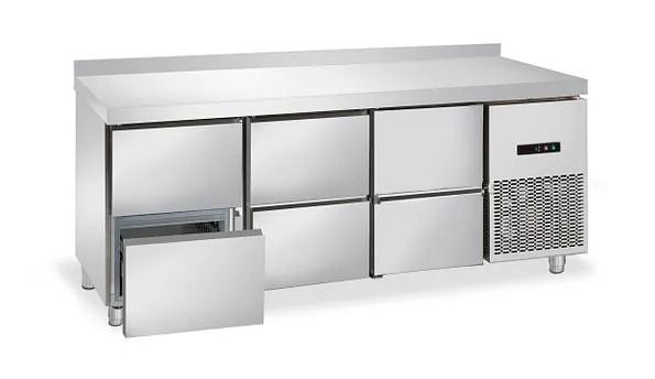 Un mostrador de acero inoxidable con cajones y refrigerador.