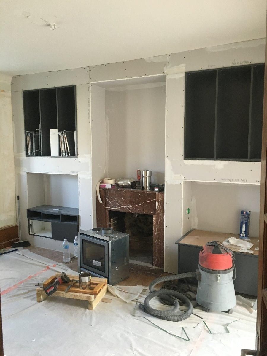 Salon avec une cheminée après les travaux de rénovation : création d'étagères murales