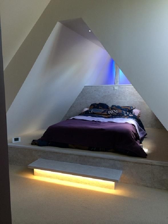 Aménagement d'une chambre avec un lit sous les toits.