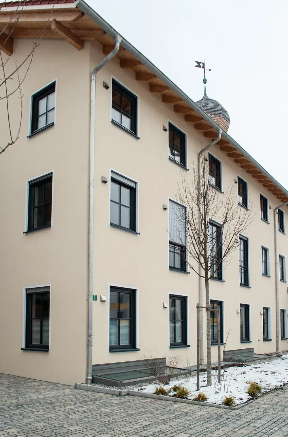 Detailansicht eines Dachstuhls mit sichtbaren Holzbalken und hell verputzter Außenwand.