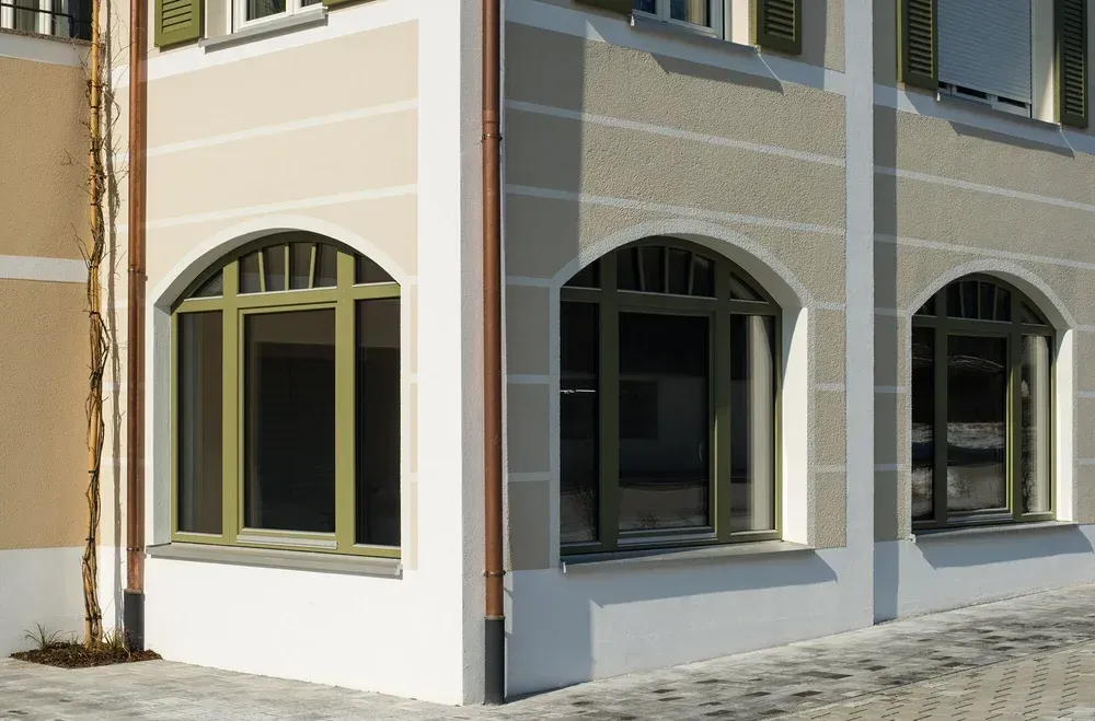Fassade eines renovierten Gebäudes mit drei Rundbogenfenstern und hellem Putz.