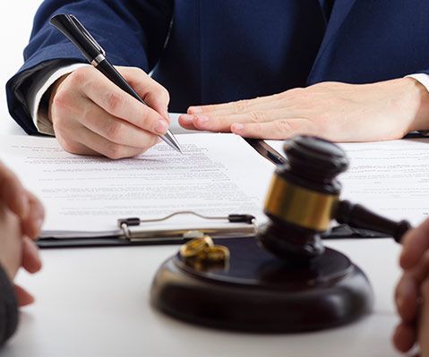 Un hombre está escribiendo en un trozo de papel al lado del mazo de un juez.