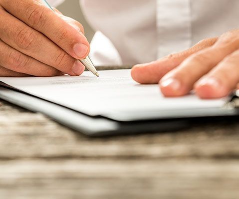 Una persona está escribiendo en un trozo de papel con un bolígrafo.