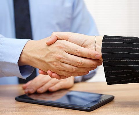 Un hombre y una mujer se dan la mano delante de una tableta.