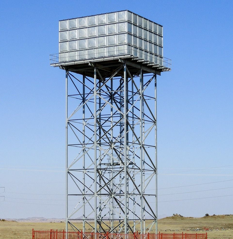 Water tank on a metal tower, providing water storage. Blue sky background.
