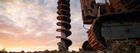 An auger drill on a construction site drills into the ground during the sunset.
