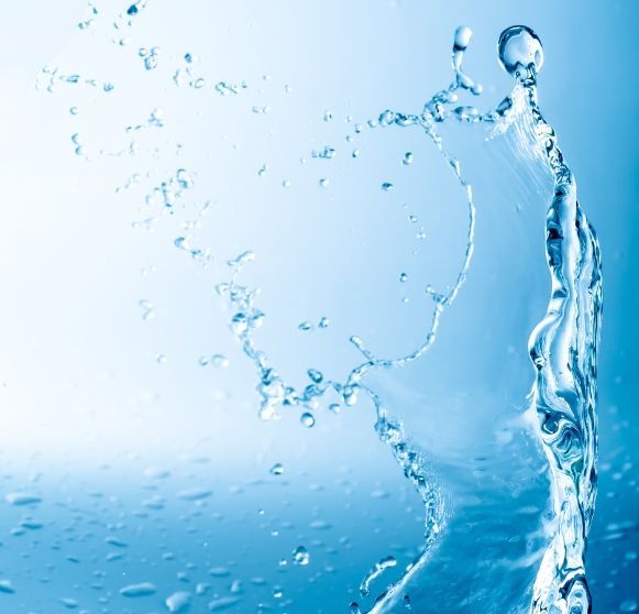 Blue drilling machine boring into the earth, surrounded by green grass.