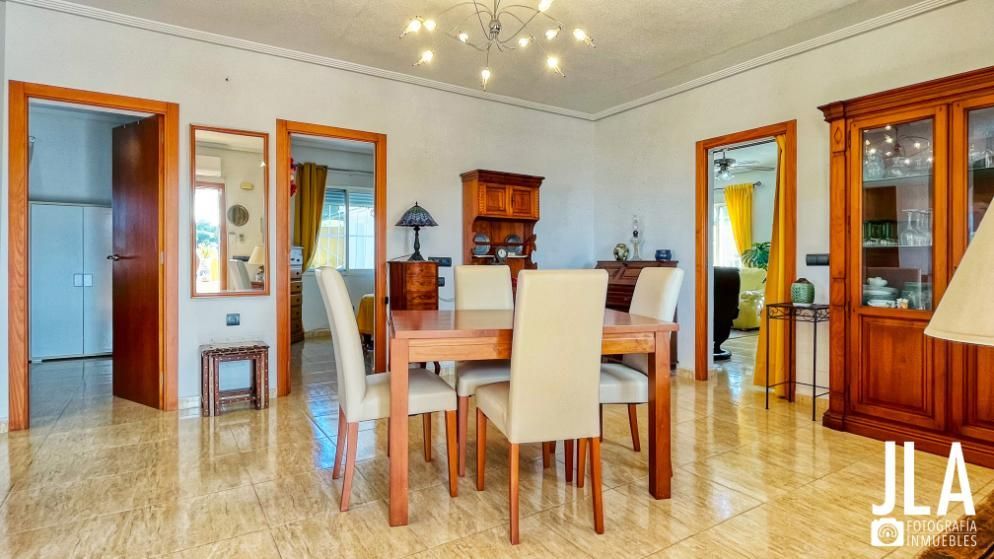 Comedor con muebles de madera, incluyendo mesa, sillas y armario. Puertas marrones y suelo de baldosas.