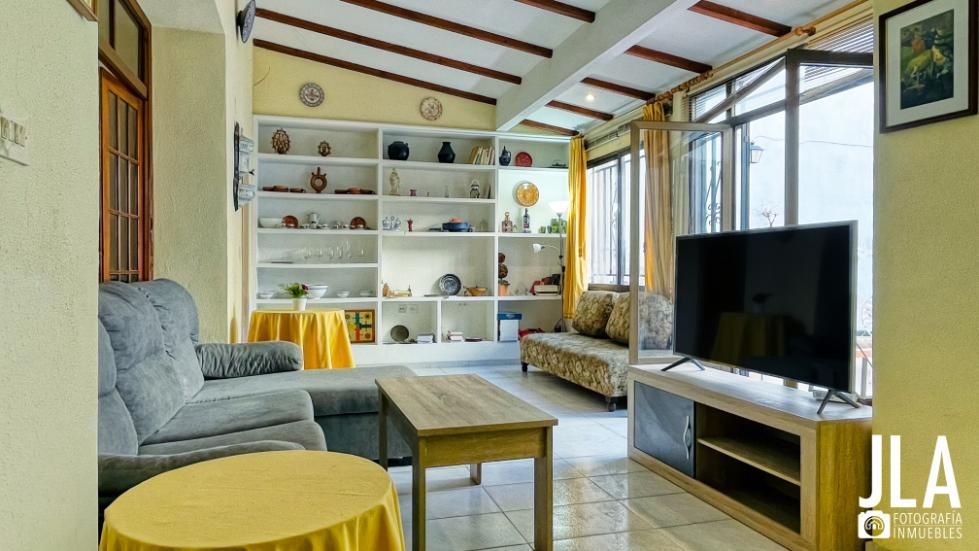 Sala de estar con sofá gris, TV, estantes empotrados que muestran la decoración y ventanas.