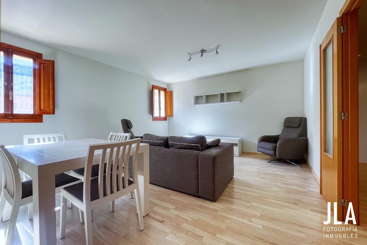 Sala de estar con mesa de comedor, sofá, sillón reclinable, pisos de madera y contraventanas de madera.