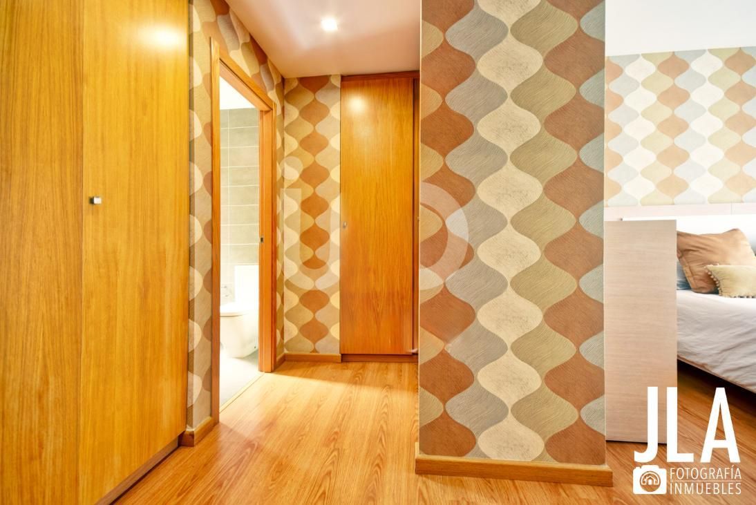 Recibidor con muebles de madera y papel pintado estampado en tonos neutros.