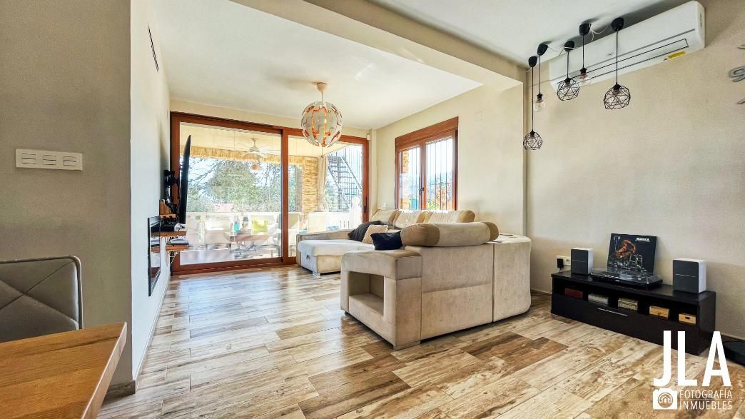 Sala de estar con piso de baldosas color canela, paredes neutrales, puertas corredizas de vidrio