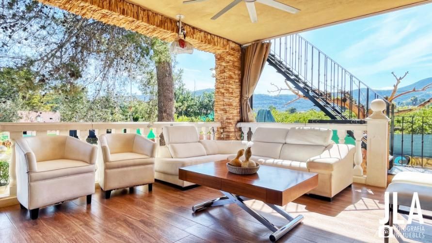 Patio con sofás blancos, mesa de café y vista a las montañas.