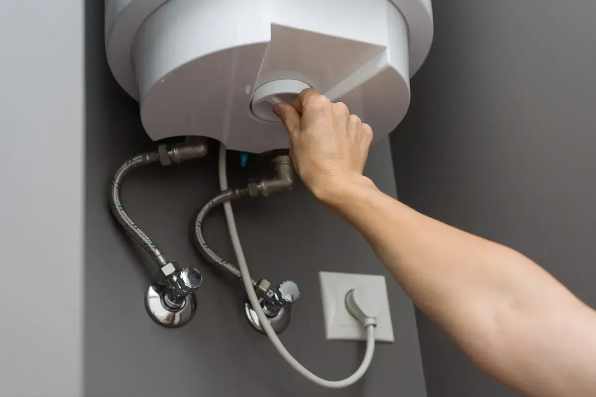 Una persona está arreglando un calentador de agua en un baño.