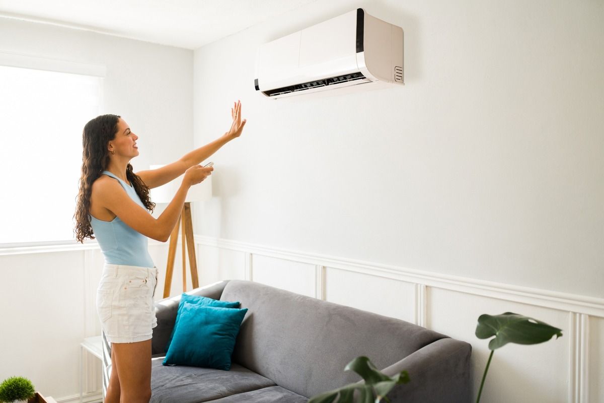 Una mujer está ajustando el aire acondicionado en una sala de estar.