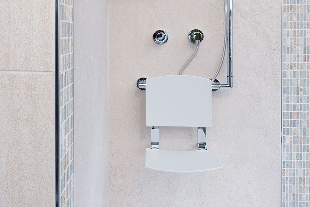Eine Dusche mit einem an der Wand befestigten Stuhl und einem Duschkopf.