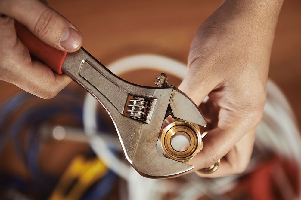 Eine Person hält einen Schraubenschlüssel über eine Mutter