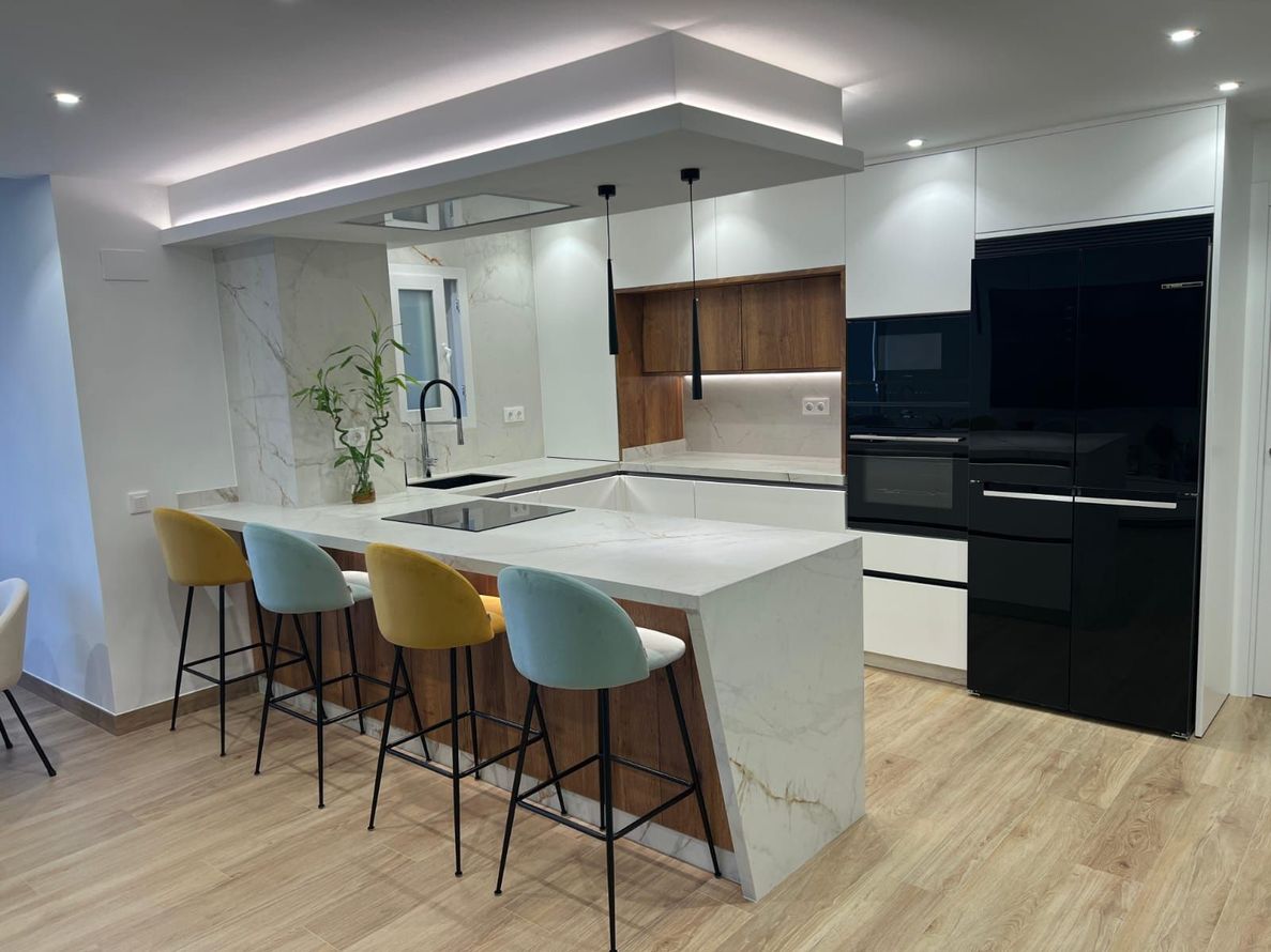Cocina moderna con refrigerador de acero inoxidable, horno empotrado, gabinetes de madera y encimera de isla de madera clara.