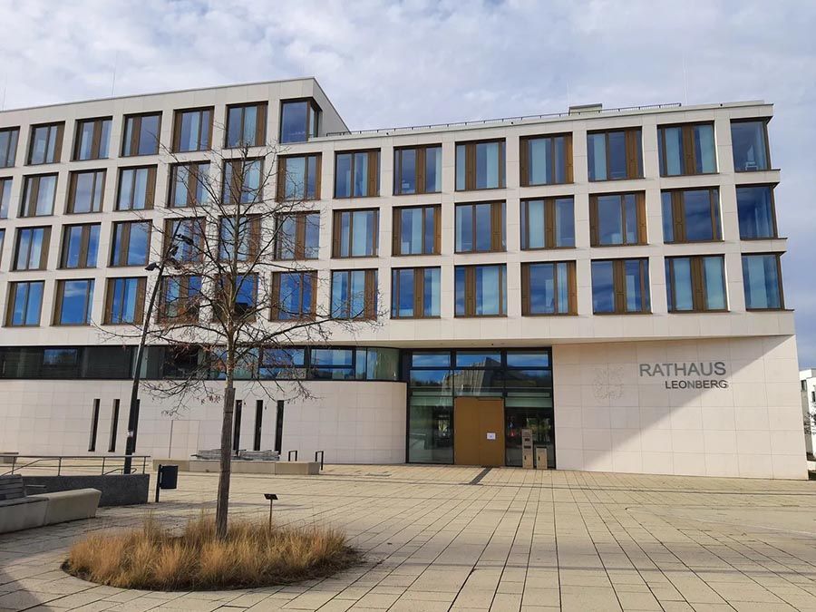 Modernes Rathaus mit großen Fenstern und dem Schild „Rathaus“, gesehen von einem Platz aus.