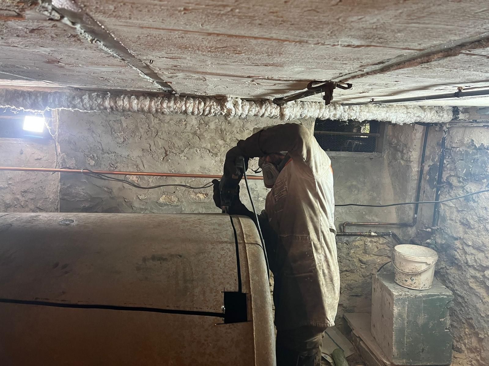 Le professionnel découpe une cuve à fioul dans une cave.