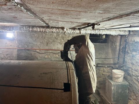 Le professionnel découpe une cuve à fioul dans une cave.