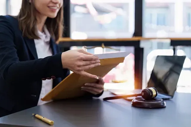Una mujer está sentada en un escritorio con una computadora portátil y un mazo de juez.