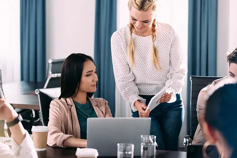 Un grupo de personas está sentada en una mesa frente a una computadora portátil.