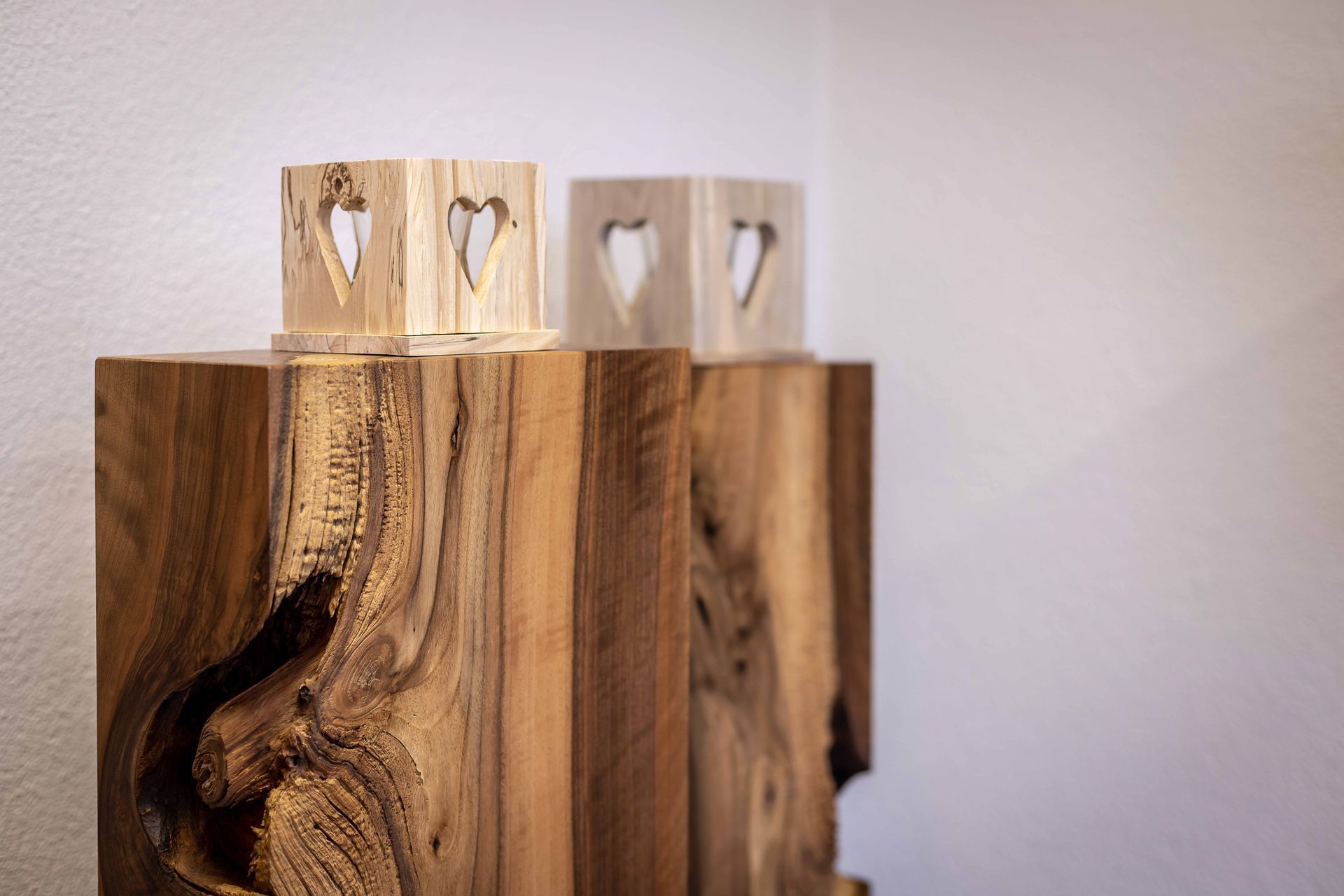 Drei Holzklötze mit eingeschnitzten Herzen liegen übereinander.