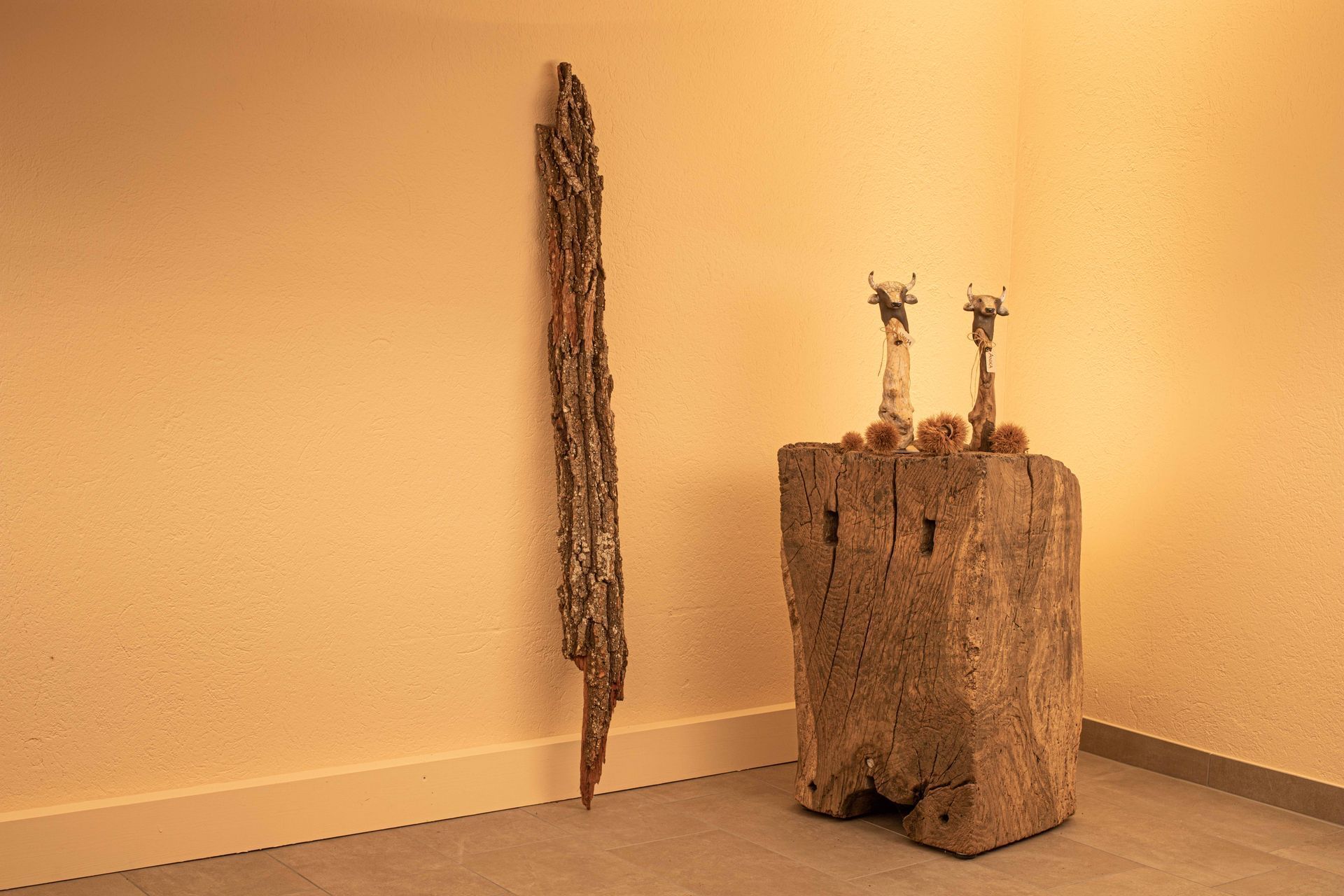 In einer Zimmerecke steht neben einer Wand eine Holzskulptur.