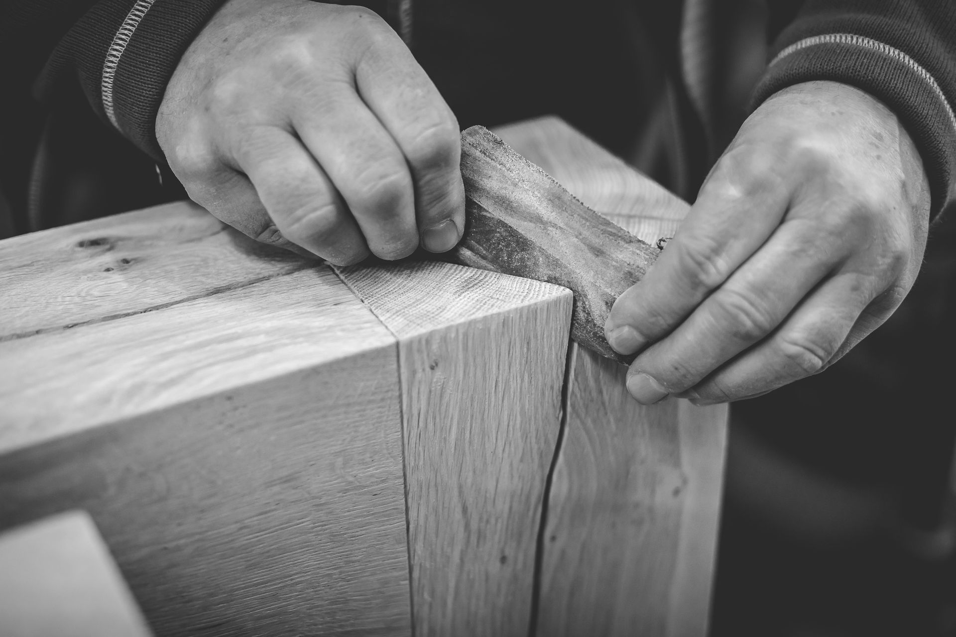 Ein Schwarzweissfoto einer Person, die ein Stück Holz schneidet.